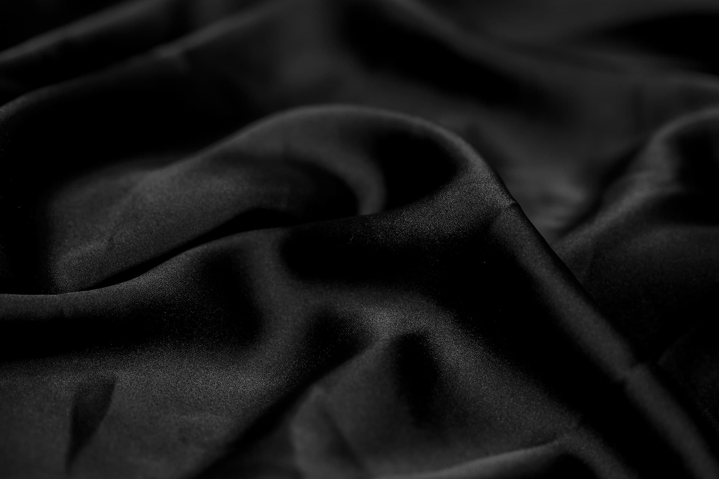 Close-up of matte black silk folds in low light.